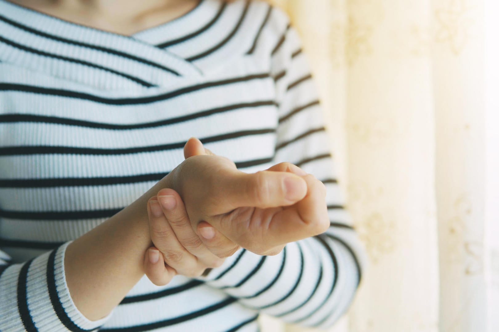 Eine Frau hat Schmerzen in der Hand: Eine Rhizarthrose kann sehr schmerzhaft sein.