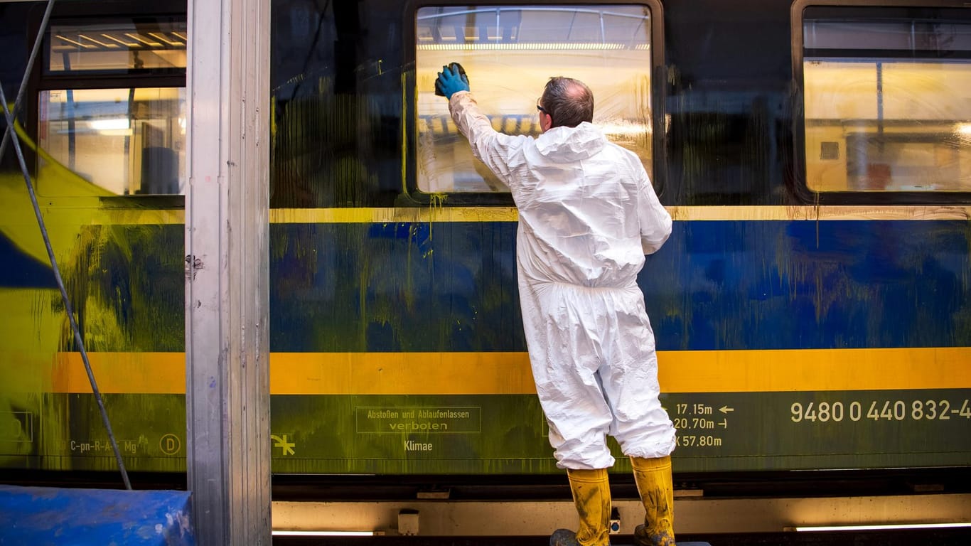 Ein Mann putzt einen Zug (Archivbild): In einer Werkstatt der Nordwestbahn wird daran gearbeitet, Graffiti von den Waggons zu entfernen.
