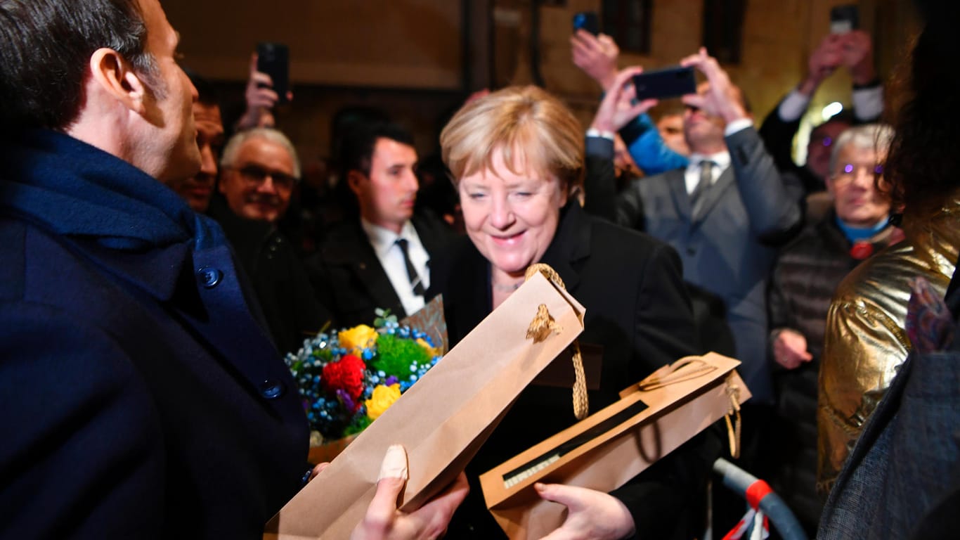 Macron und Merkel in Beaune: Die geschäftsführende Kanzlerin freut sich über Blumen und eine Flasche Wein.