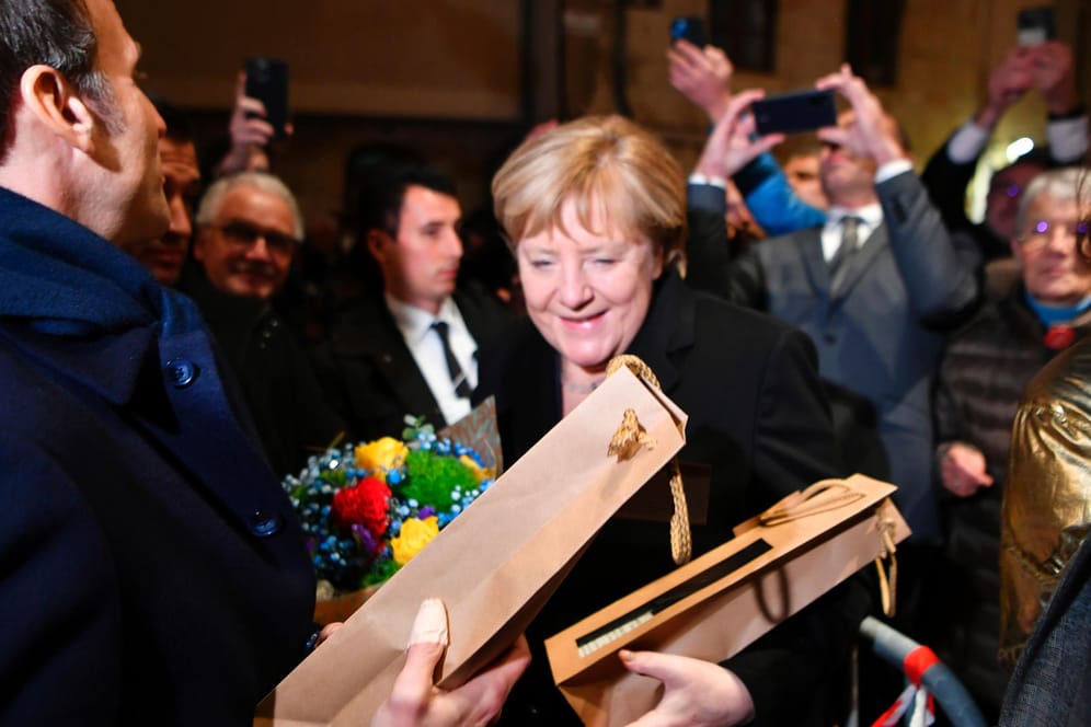 Macron und Merkel in Beaune: Die geschäftsführende Kanzlerin freut sich über Blumen und eine Flasche Wein.