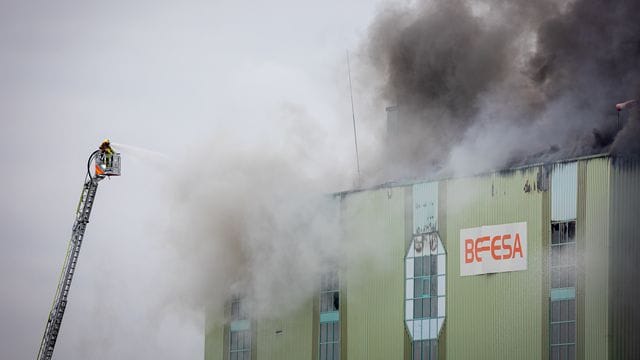 Feuerwehrleute löschen von einer Drehleiter aus den Brand einer Industriehalle am Brinker Hafen: Warum das Feuer ausgebrochen ist, ist noch unklar.