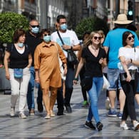 Menschen mit Maske und ohne: Der Druck auf Ungeimpfte steigt.
