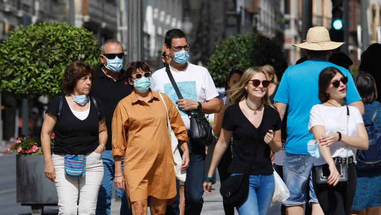 Menschen mit Maske und ohne: Der Druck auf Ungeimpfte steigt.