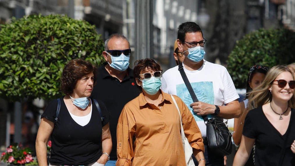 Menschen mit Maske und ohne: Der Druck auf Ungeimpfte steigt.