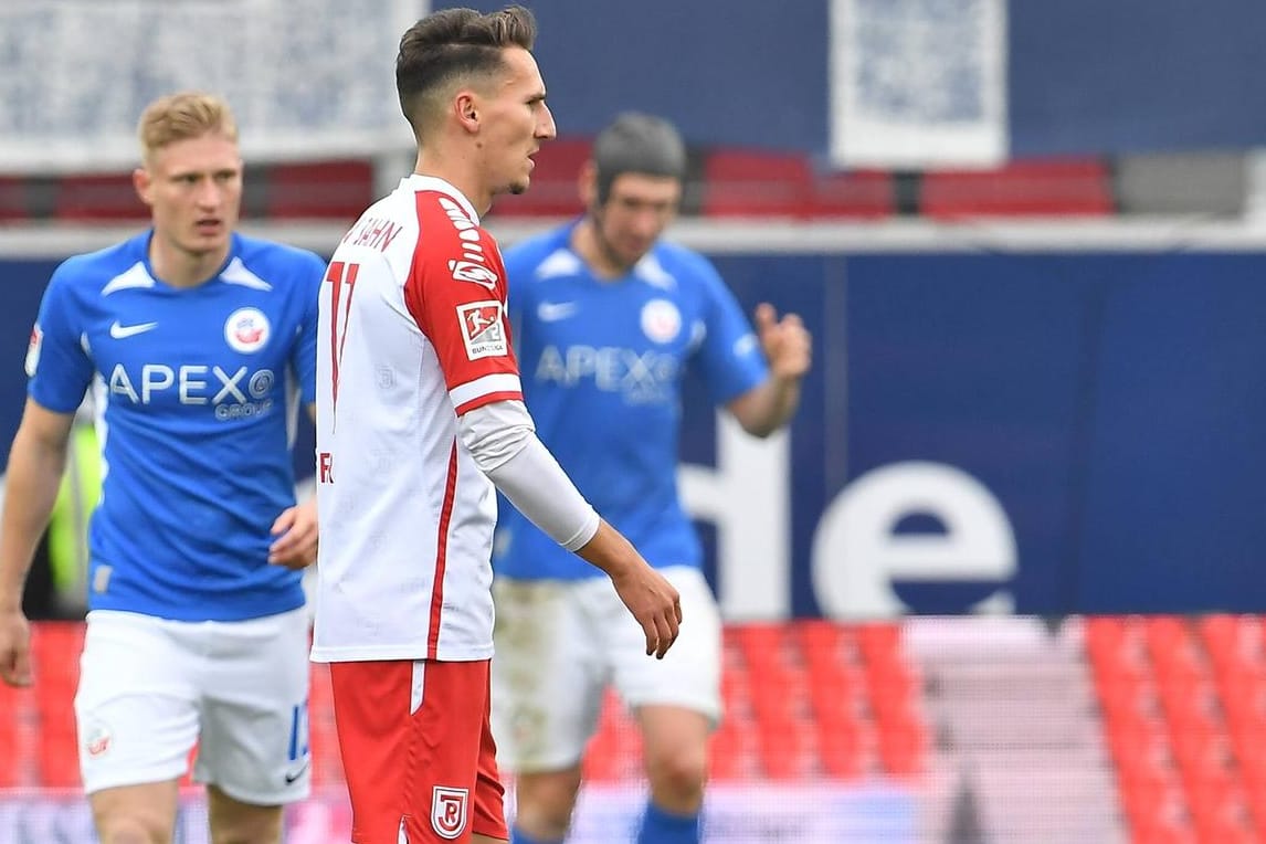 Regensburgs Konrad Farber (vorne) niedergeschlagen, Rostocks Spieler jubeln im Hintergrund: Die Partie in Regensburg wurde zur Überraschung.