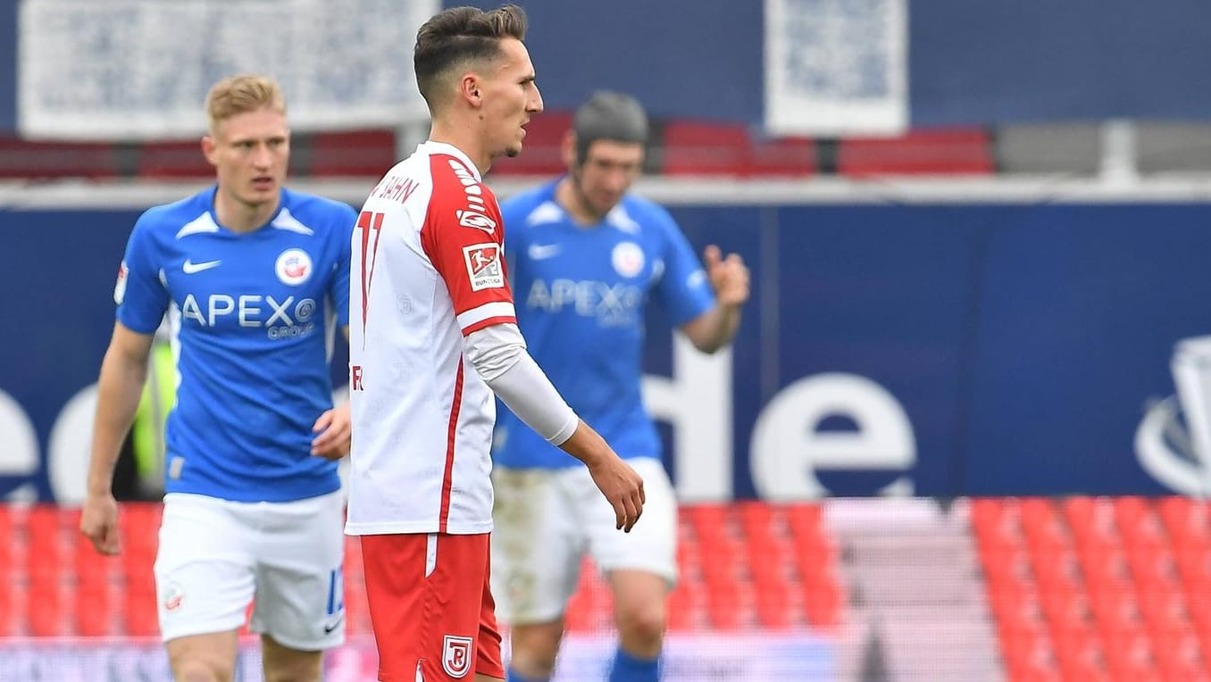 Regensburgs Konrad Farber (vorne) niedergeschlagen, Rostocks Spieler jubeln im Hintergrund: Die Partie in Regensburg wurde zur Überraschung.