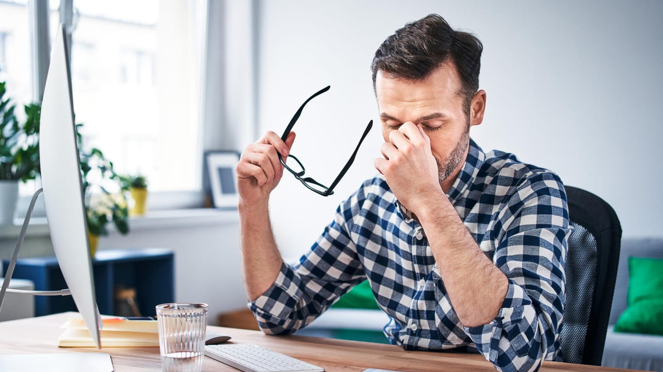 Müde wirkender Mann am Schreibtisch: Eine Hämochromatose geht zu Beginn meist mit unspezifischen Symptomen wie Abgeschlagenheit, verminderter Leistungsfähigkeit oder Gelenkschmerzen einher.