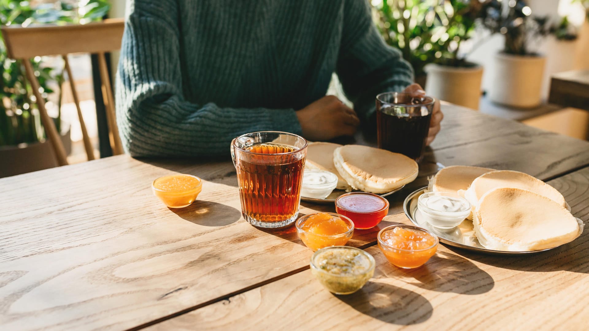 Frau am Esstisch mit einem Glas schwarzen Tee: Schwarzer Tee hemmt die Eisenaufnahme.