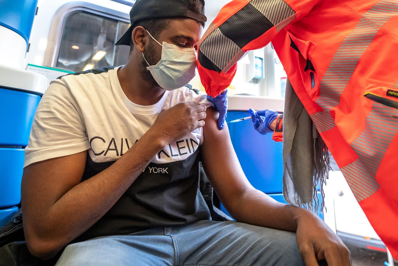 Ein Mann lässt sich in einem Krankenwagen gegen Corona impfen: Die große Zahl der Ungeimpften lässt die Diskussion über eine Impfplicht wieder aufflammen.