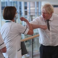 Der britische Premierminister Boris Johnson begrüßt Mitarbeiterinnen in einem Krankenhaus: Weil der dabei keine Maske trug, hagelte es Kritik vom Gesundheitsdienst NHS.