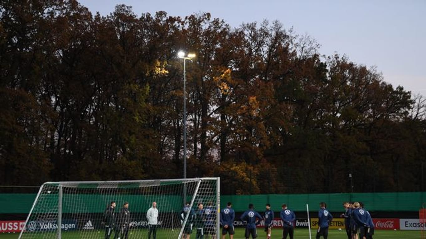 Zum Training hat Bundestrainer Flick die Mannschaft im Halbkreis vor einem Tor versammelt.