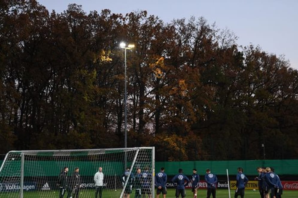 Zum Training hat Bundestrainer Flick die Mannschaft im Halbkreis vor einem Tor versammelt.
