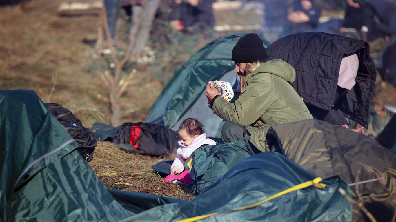Ein Mann ruht sich mit einem Kind an der belarussisch-polnischen Grenze aus: Unter den Migranten sind auch Familien mit kleinen Kindern.
