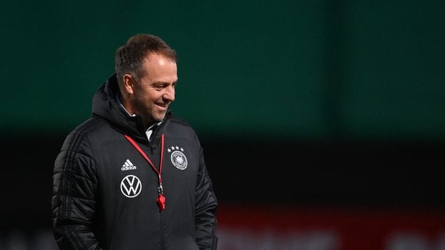 Der Mann mit der roten Trillerpfeife: Bundestrainer Hansi Flick steht lächelnd auf dem Platz.
