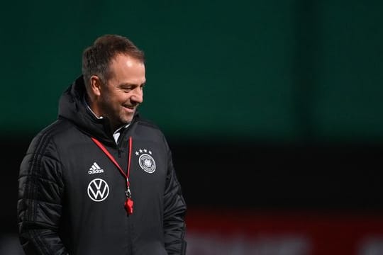Der Mann mit der roten Trillerpfeife: Bundestrainer Hansi Flick steht lächelnd auf dem Platz.