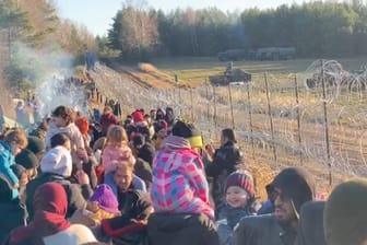 Migranten stehen neben einem Zaun an der Grenze zu Polen: Tausende sollen die Hürde in der vergangenen Nacht durchbrochen haben.
