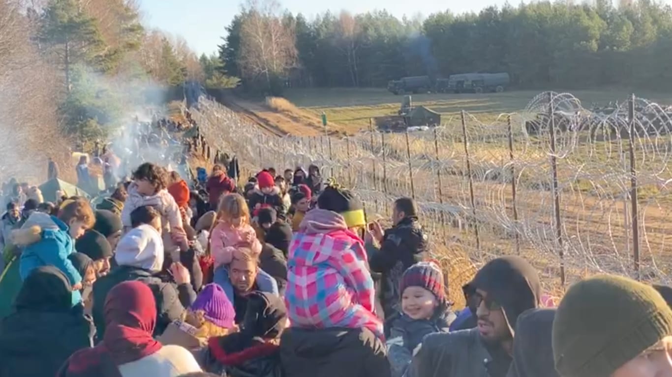 Migranten stehen neben einem Zaun an der Grenze zu Polen: Tausende sollen die Hürde in der vergangenen Nacht durchbrochen haben.