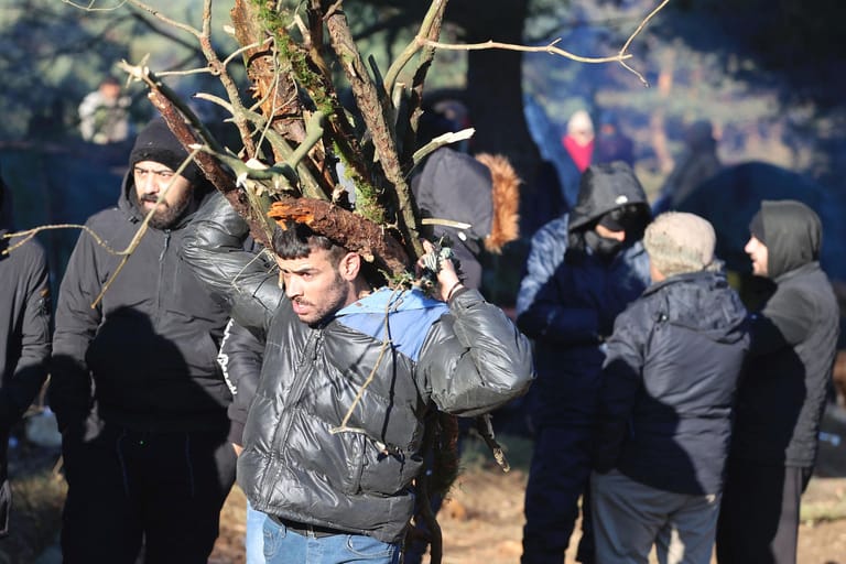 Ein Mann trägt Brennholz: Die niedrigen Temperaturen im Grenzgebiet sind eine große Gefahr für die Migranten.
