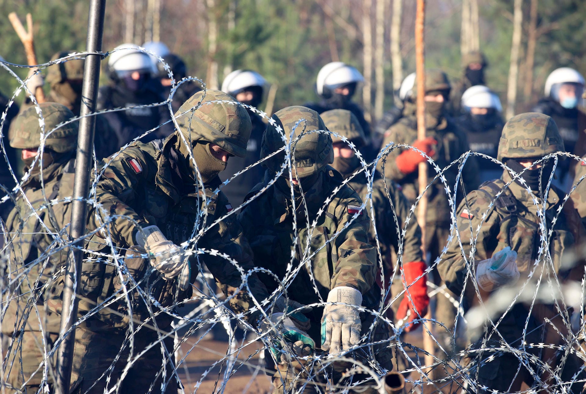 Polnische Polizisten und Soldaten stehen am Stacheldraht: Er soll den Grenzübertritt der Migranten verhindern.