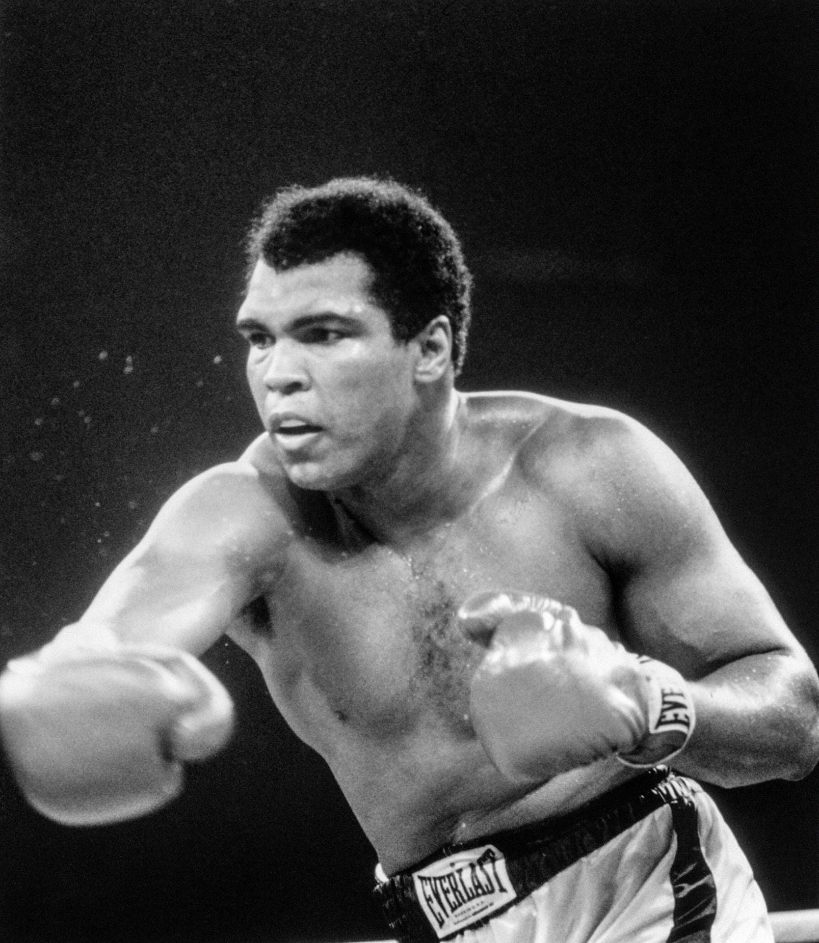 Muhammad Ali: Der weltberühmte Boxer im Jahr 1977. Er ist der einzige Sportler seiner Branche, der drei Mal in seiner Karriere den Titel des unumstrittenen Weltmeisters gewinnen konnte. 1984 wurde bei Ali das Parkinson-Syndrom diagnostiziert. Dennoch versuchte der Boxer am öffentlichen Leben teilzuhaben, er starb 2016 in Folge eines septischen Schocks.
