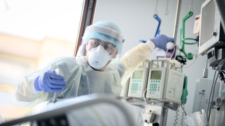 Ein Intensivpfleger arbeitet auf der Intensivstation eines Krankenhauses (Symbolbild): Operationen könnten abgesagt werden, weil das Personal für die Pflege von Covid-Patienten benötigt wird.