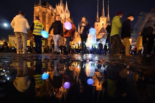 Familien mit Kindern gehen mit Laternen über den Domplatz