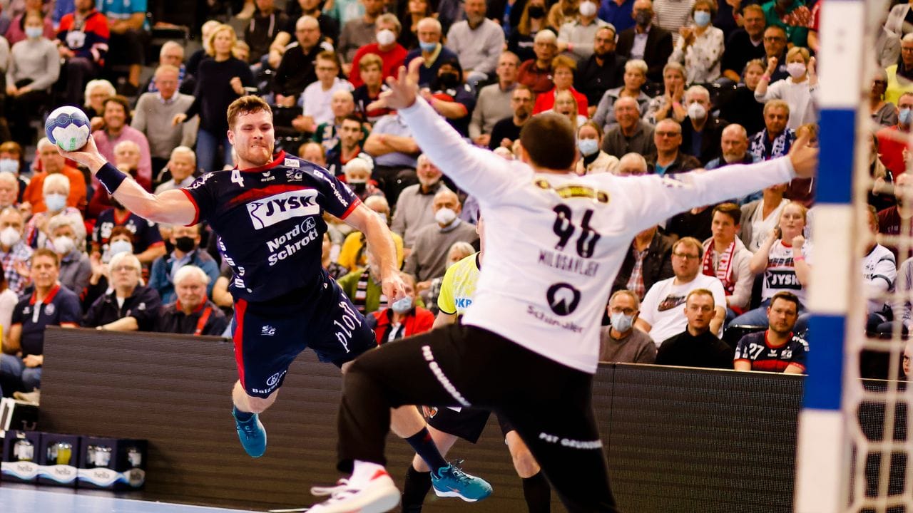 Flensburgs Johannes Golla (l) wirft gegen Füchse-Torwart Dejan Milosavljev auf das Tor.