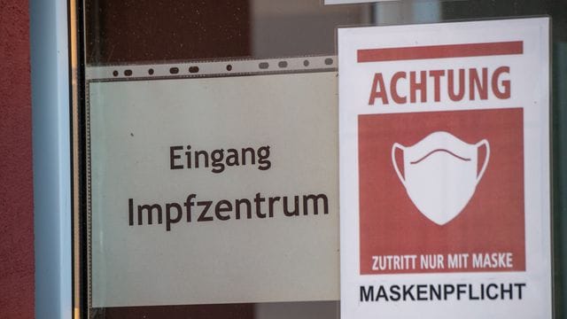 Ein Schild weist den Weg zu einem Corona-Impfzentrum.