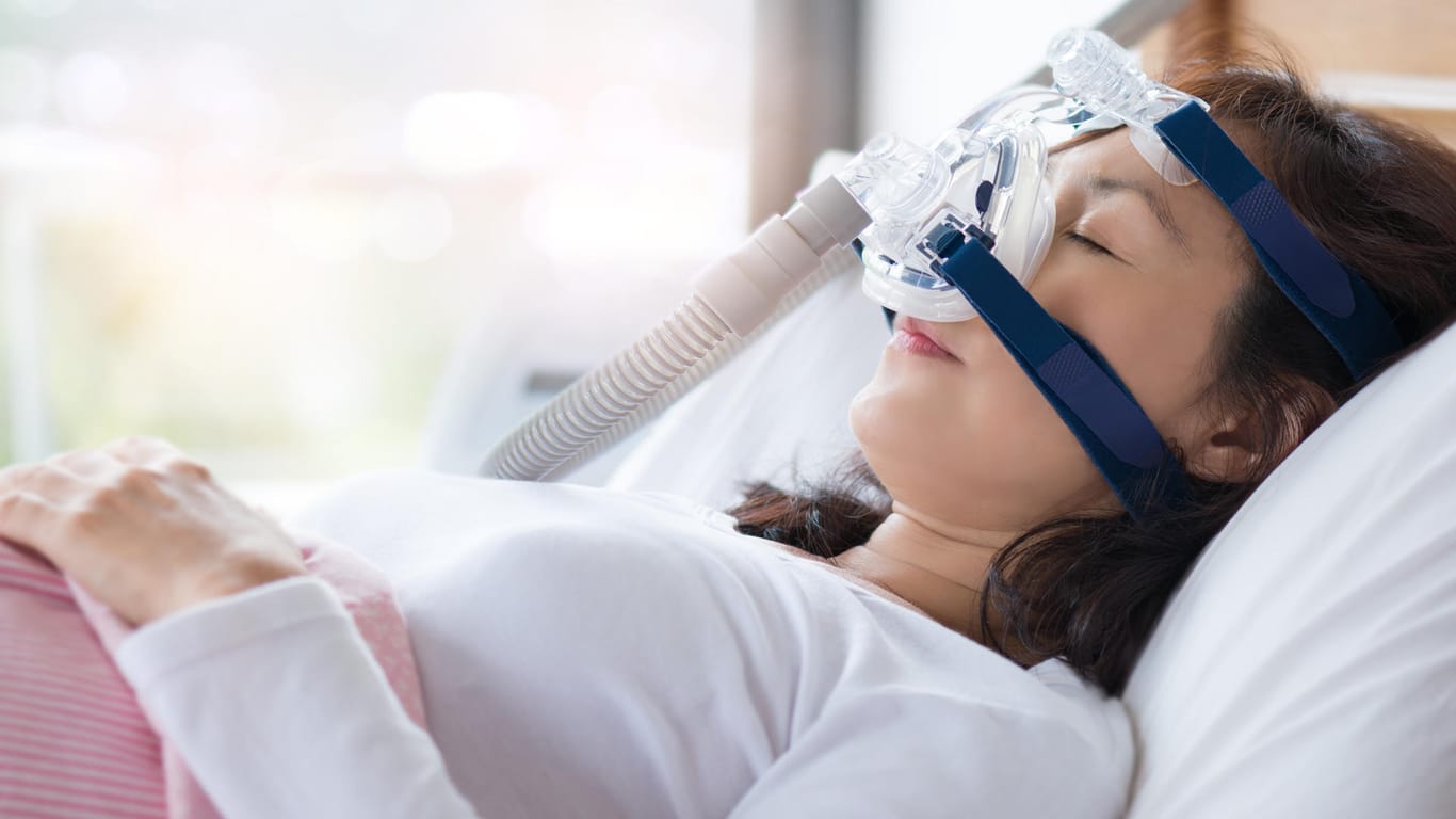 Schlafende Frau mit CPAP-Gerät: Regelmäßig angewendet kann die Atemtherapie eine Schlafapnoe und die damit verbundenen Beschwerden deutlich lindern.