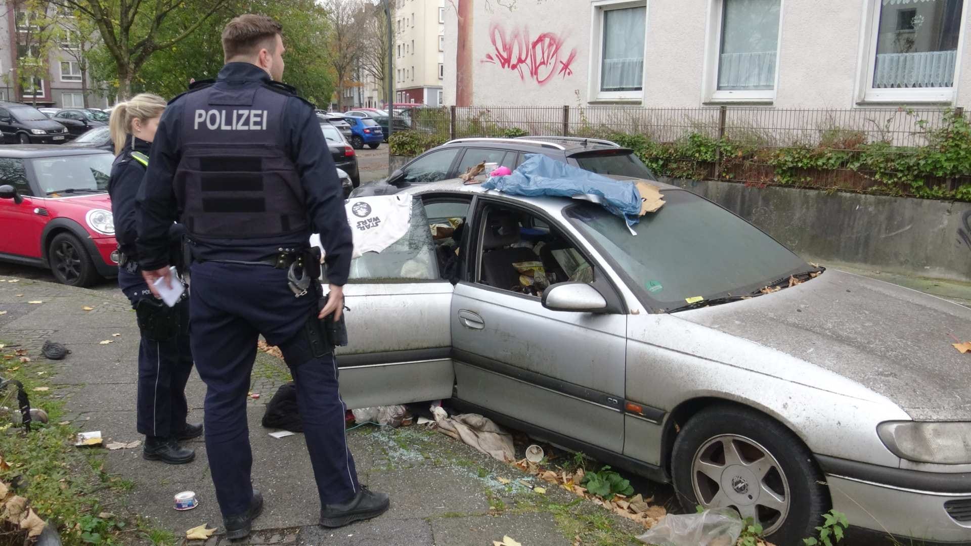 Zwei Polizisten begutachten den Pkw: Eine eingeschlagene Scheibe war der Grund für den Einsatz.