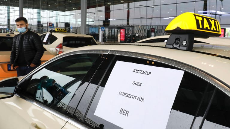 "Jobcenter oder Ladegerecht für BER" steht auf einem Taxi, das an einer Demonstration teilnimmt (Archivbild): Wer keine Ladeerlaubnis hat, darf Fahrgäste zwar zum BER bringen, jedoch keine vom Flughafen mitnehmen.