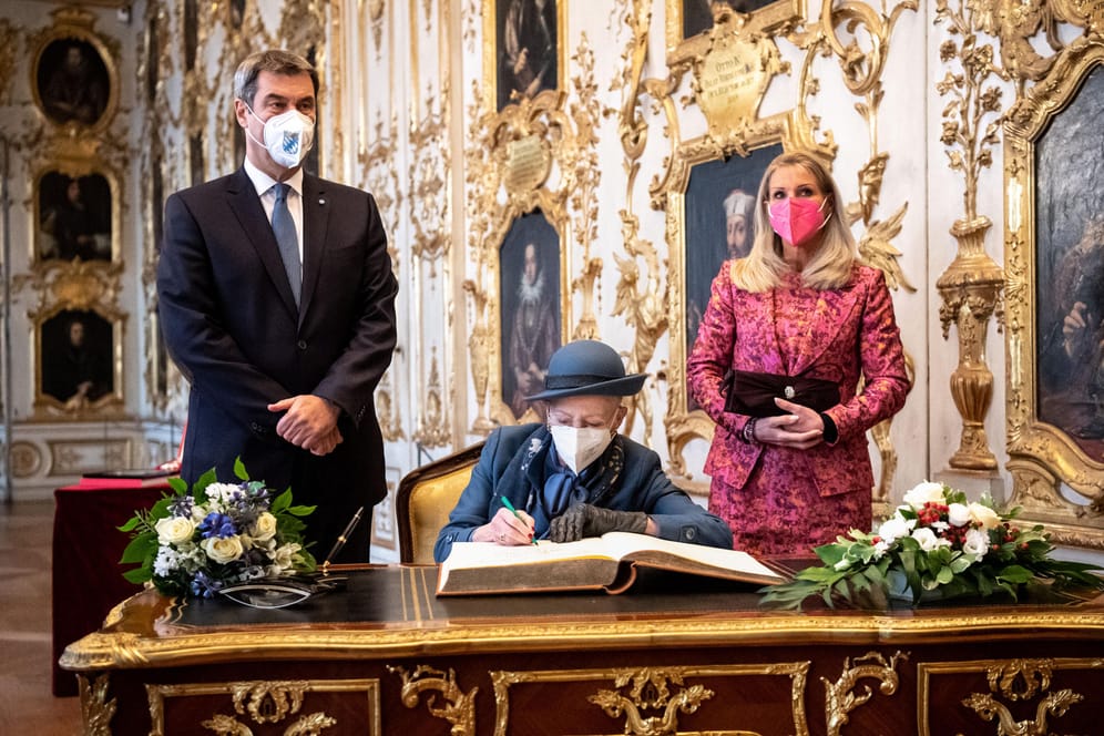Königin Margrethe II. von Dänemark trägt sich in der Residenz München in das Gästebuch der Bayerischen Staatsregierung ein (Archivbild): Links von ihr der bayerische Ministerpräsident, rechts von ihr seine Frau Karin Baumüller-Söder.