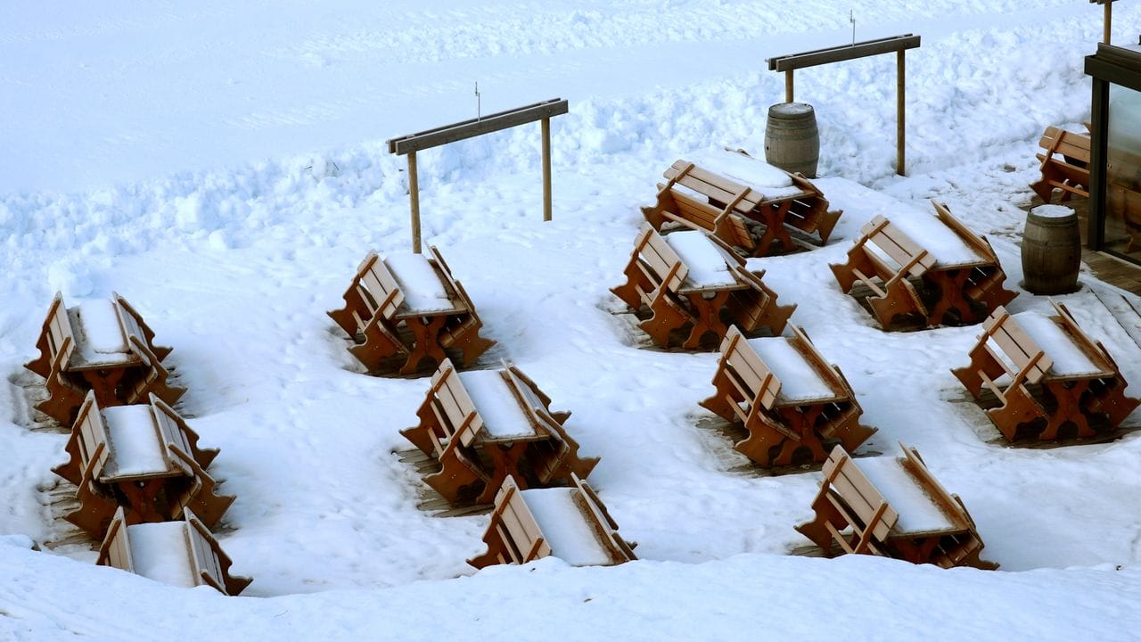 Schnee bedeckt Bänke und Tische an einer gesperrten Skipiste. Schnee bedeckt Bänke und Tische an einer gesperrten Skipiste.