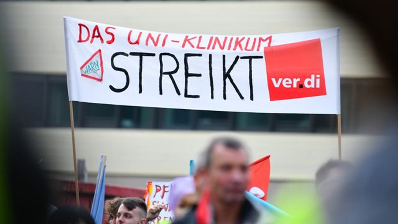 Streikende Beschäftigte halten ein Transparent mit der Aufschrift "Das Uni-Klinikum streikt" hoch. Ende November steht die dritte Verhandlungsrunde in Potsdam an.