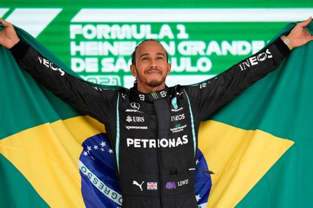 Grand-Prix-Sieger Lewis Hamilton steht mit einer brasilianischen Flagge auf dem Podium.