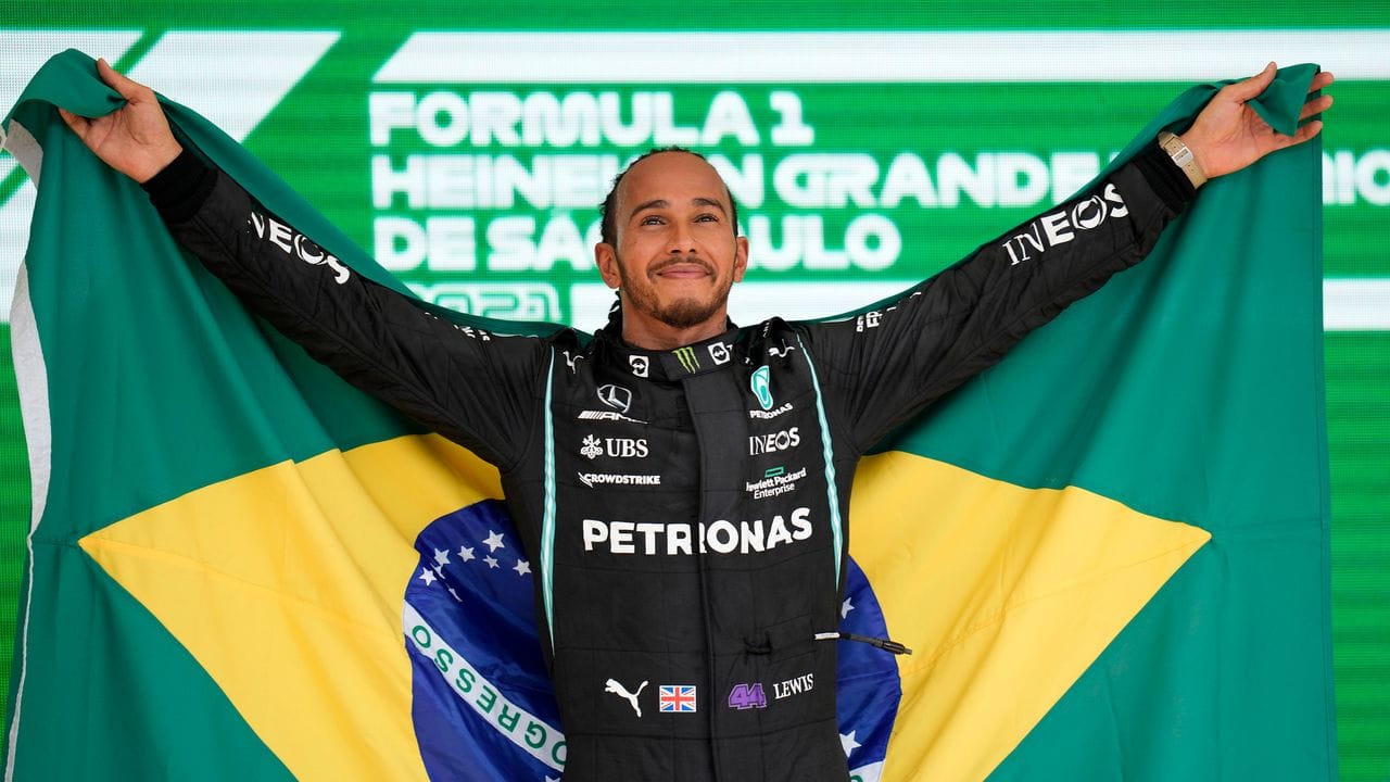 Grand-Prix-Sieger Lewis Hamilton steht mit einer brasilianischen Flagge auf dem Podium.