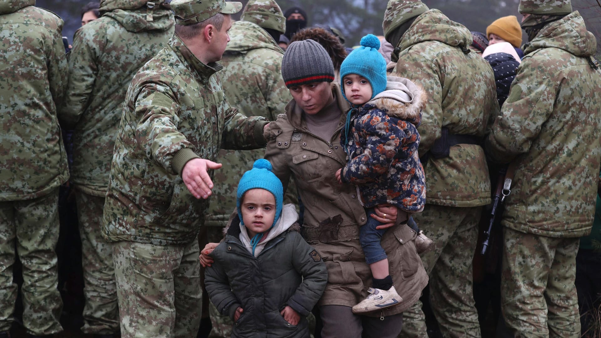 Mann mit Kindern geht an belarussischen Soldaten vorbei: Polens Grenzschutz hat den Sicherheitskräften in Belarus vorgeworfen, die an der gemeinsamen Grenze feststeckenden Migranten auf einen Durchbruch der Sperranlage vorzubereiten.