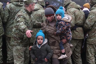 Mann mit Kindern geht an belarussischen Soldaten vorbei: Polens Grenzschutz hat den Sicherheitskräften in Belarus vorgeworfen, die an der gemeinsamen Grenze feststeckenden Migranten auf einen Durchbruch der Sperranlage vorzubereiten.