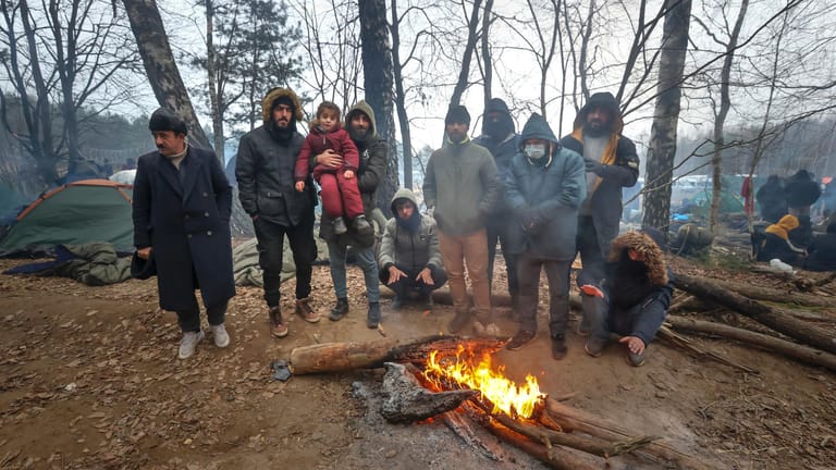 Migranten versammeln sich an der belarussisch-polnischen Grenze an einem Feuer, um sich zu wärmen: Merkel hat Russlands Präsidenten Putin angesichts der dramatischen Lage gebeten, Einfluss auf die autoritäre Regierung in Minsk zu nehmen.