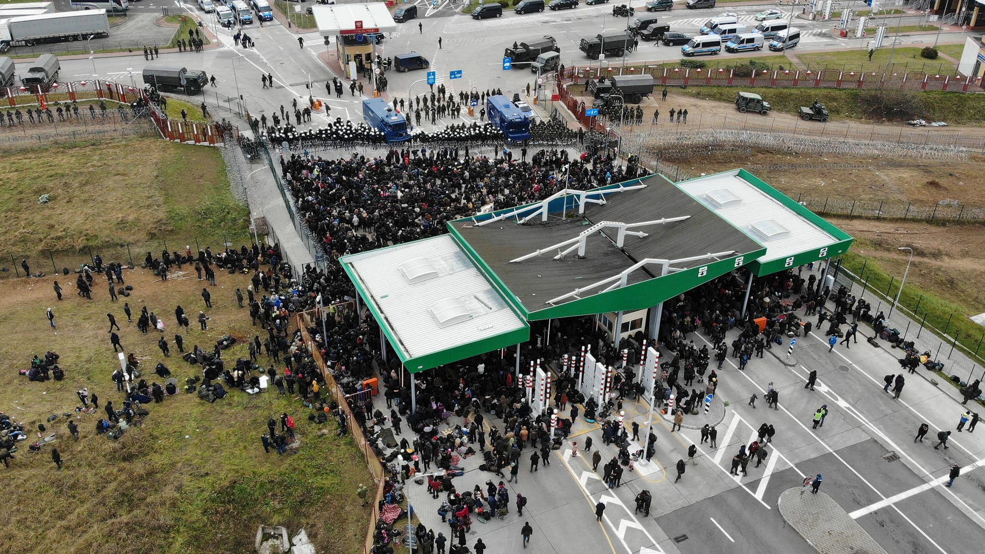 Flüchtlinge in Belarus (vorn) an der Grenze zu Polen (hinten) am Montag am Grenzort Kuźnica : Angst vor einem zweiten 2015.