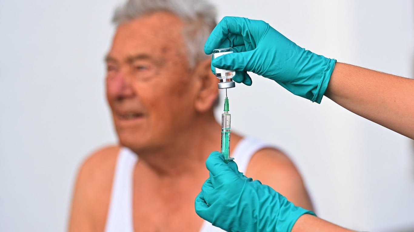 Eine Spritze mit einer Boosterimpfung wird für einen älteren Mann aufgezogen (Symbolbild): Das RKI meldet viele Landkreise mit Inzidenzen über 1.000.