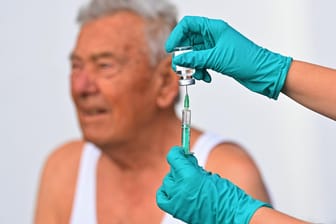 Eine Spritze mit einer Boosterimpfung wird für einen älteren Mann aufgezogen (Symbolbild): Das RKI meldet viele Landkreise mit Inzidenzen über 1.000.