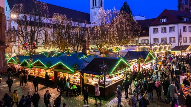 Besucher gehen über den Freiburger Weihnachtsmarkt (Archivbild): Das Colombischlössle soll mit der Eröffnung des Marktes wieder festlich erstrahlen.