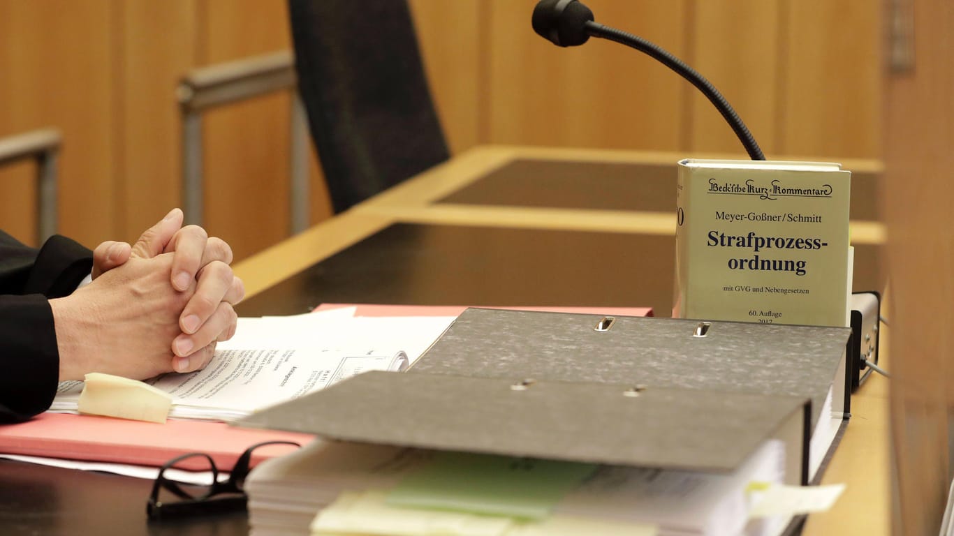 Ein Anwalt sitzt mit gefalteten Händen im Gerichtssaal (Symbolbild): Am Kölner Landgericht wird aktuell der Fall eines 19-Jährigen verhandelt, der versucht haben soll, die Mutter einre Mitschülerin zu ermorden.