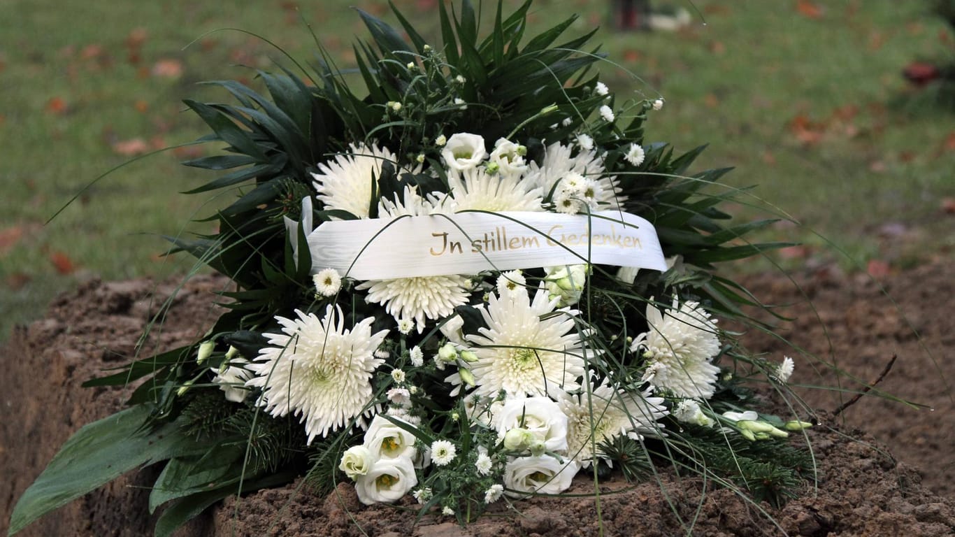 "In stillem Gedenken" steht auf einem Kranz (Symbolbild): Auf einem Leipziger Friedhof haben Unbekannte drei Männer attackiert.