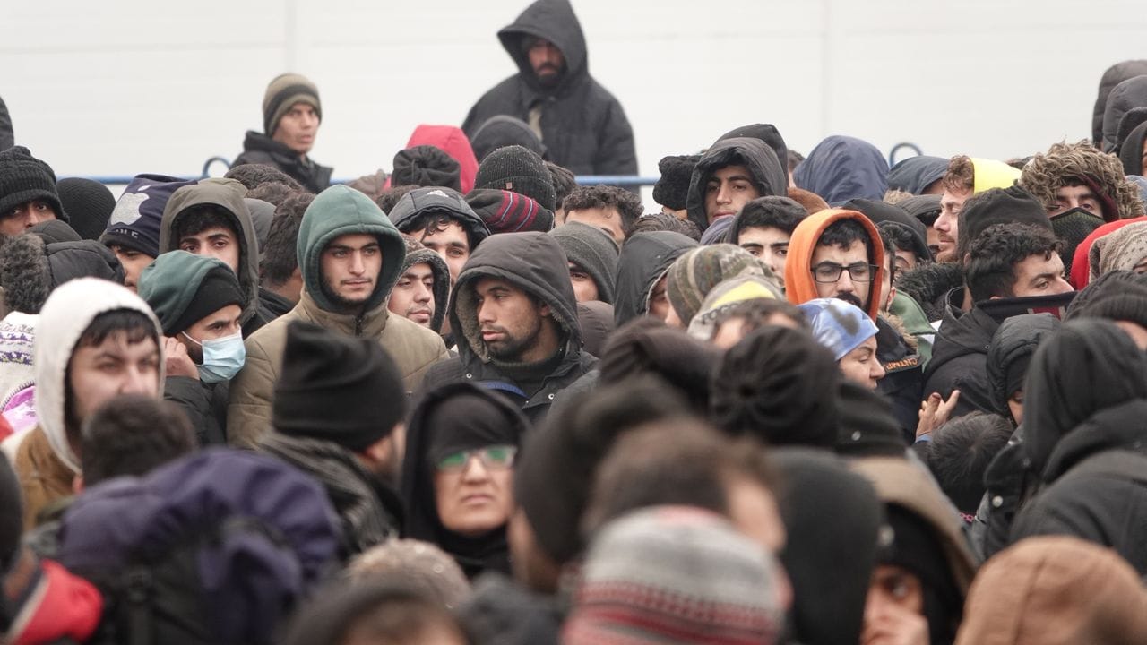 Migranten warten vor einer Lagerhalle in der Nähe der Grenze.
