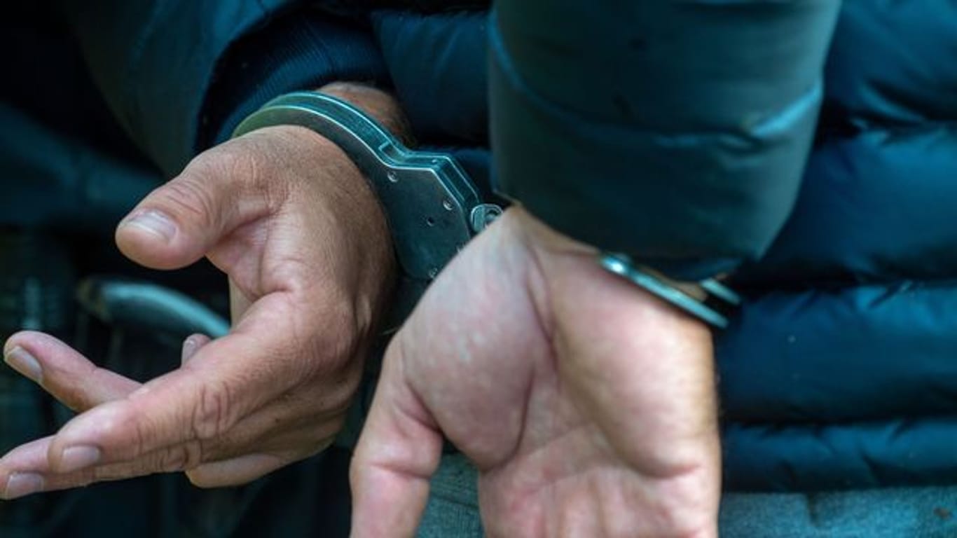 Ein Mann trägt Handschellen (Symbolbild): In München soll ein Jugendlicher einen 18-Jährigen mit einem Messer verletzt haben.