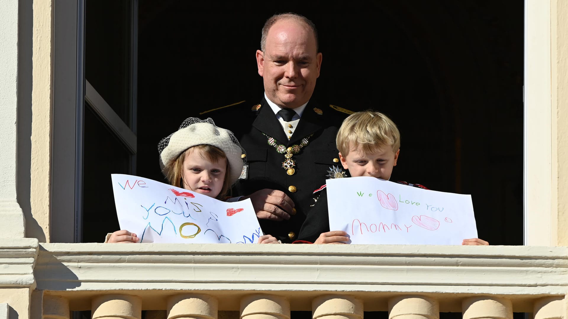 Prinzessin Gabriella und Prinz Jacques zeigen sich mit selbstgemalten Plakaten auf dem Balkon.