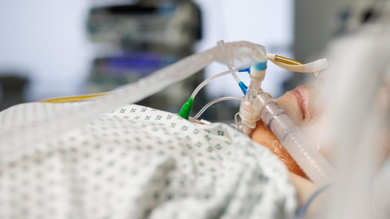 Ein über einen Luftröhrenschnitt beatmeter Corona-Patient liegt in einem Intensivbett-Zimmer: In den kommenden Wochen wird die Zahl der Corona-Infizierten, die intensivmedizinische Versorgung brauchen noch weiter steigen.