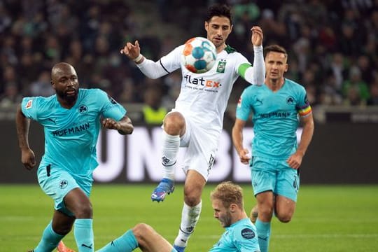 Gladbachs Lars Stindl (M) lässt sich von den Fürther Spielern nicht aufhalten.
